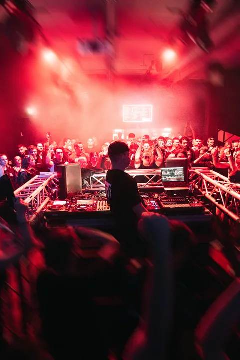 DRKNSS am DJ-Pult vor einer rot beleuchteten Crowd bei Rave Intoxication